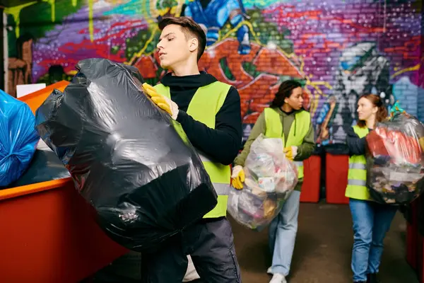 Young volunteers in gloves and safety vests sorting trash in a room together, demonstrating eco-conscious efforts. — Photo de stock