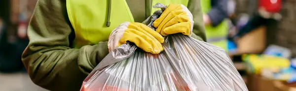 Young volunteers in gloves and safety vests sorting trash on a city street. - foto de stock