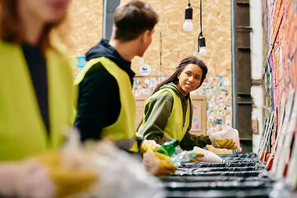Group of young volunteers in gloves and safety vests sorting trash near a wall for a cleaner environment. — Fotografia de Stock