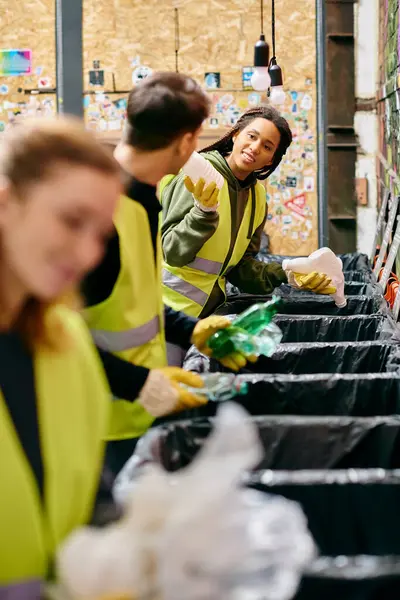 Young volunteers in gloves and safety vests sort through trash at a table filled with waste during a community clean-up event. - foto de stock