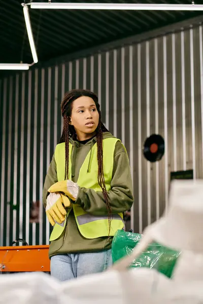 A young volunteer, eco-conscious in gloves and a yellow safety vest, while sorting waste. — Foto stock