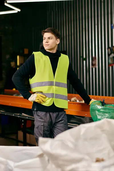 A young volunteer in gloves and safety vest sorting waste in a warehouse. — стоковое фото
