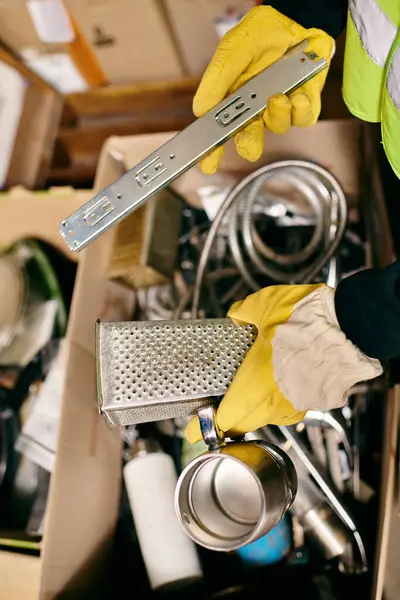 Young volunteer in yellow gloves and safety vest sorting waste with a metal grate in hand. — Stock Photo