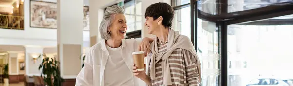 A tender moment between a loving senior lesbian couple, standing together in a hotel. — Stock Photo