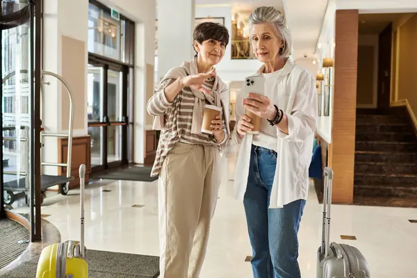 Senior lesbian couple stand together in a lobby. — Stock Photo