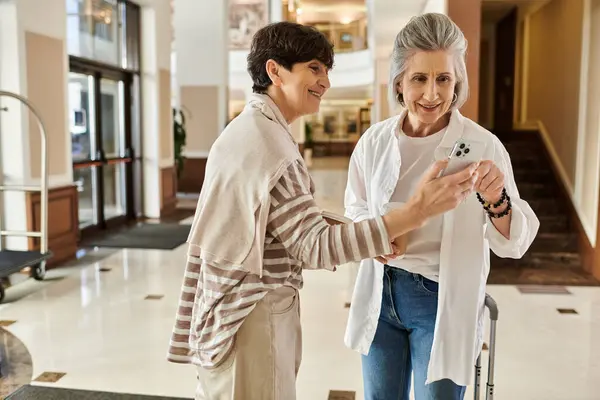 Senior lesbian couple share a moment while looking at a cell phone. — Stock Photo