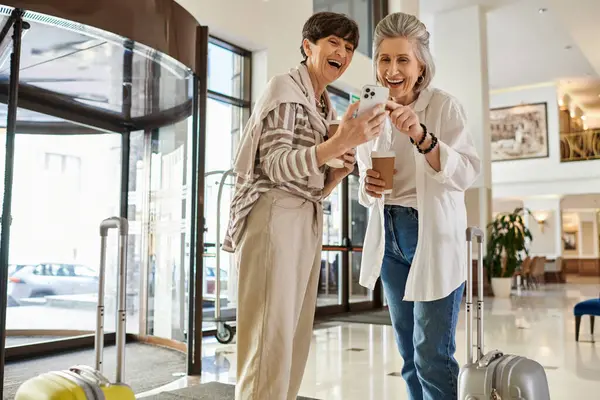 Loving tender senior lesbian couple standing closely together in a hotel. — Stock Photo