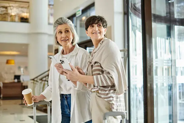 Senior lesbica coppia condividere un amorevole momento in un hotel lobby. — Foto stock