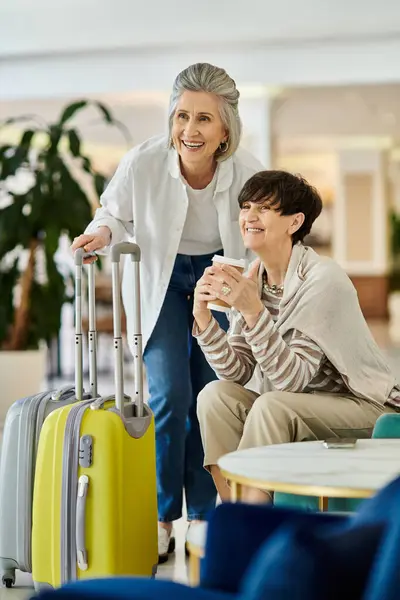 Coppia lesbica anziana che abbraccia, trasporta bagagli in un hotel. — Foto stock