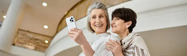 Senior lesbian couple joyfully taking a picture with her cell phone. — Stock Photo