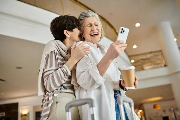 Senior lesbiana pareja en un hotel captura un momento con su teléfono. - foto de stock