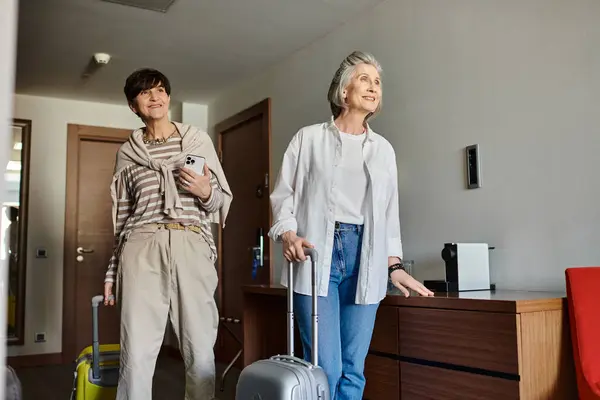 Senior coppia lesbica stand con bagagli in camera d'albergo. — Foto stock