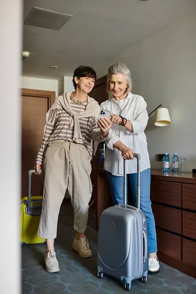 Due anziani lesbiche partner in piedi accanto a vicenda con bagagli. — Foto stock