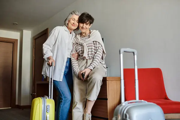 Two senior lesbian women with luggage standing together. — Stock Photo