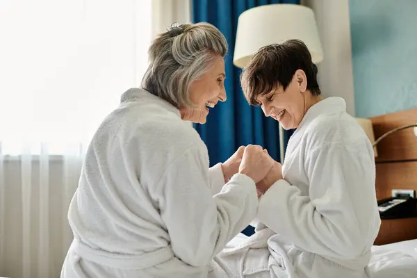 Due donne lesbiche anziane che condividono un momento tenero in una camera da letto. — Foto stock