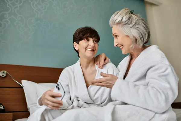 Старшая лесбийская пара разделяет нежный момент на кровати. — стоковое фото