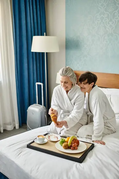 Casal lésbico sênior compartilhando um momento terno em uma cama acolhedora. — Fotografia de Stock