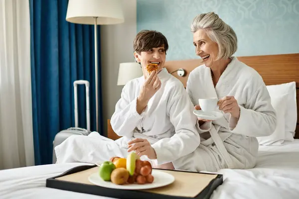 Couple of senior women sitting comfortably on a bed. — Stock Photo