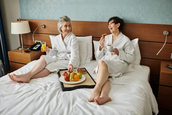 Anziani che si abbracciano sul letto in camera d'albergo. — Foto stock
