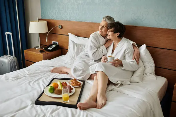 Senior couple lesbienne assis tendrement sur le dessus d'un lit confortable. — Photo de stock