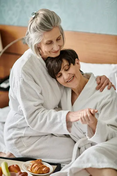 Tender moment between loving senior lesbian couple, hugging in bed. — Stock Photo