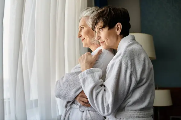 Women in a bathrobe stand by a window. — Stock Photo