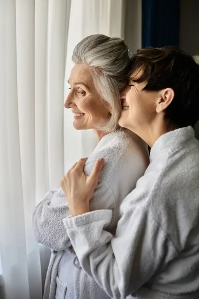 Senior lesbian couple in a bathrobe peacefully enjoy the view together. — Stock Photo