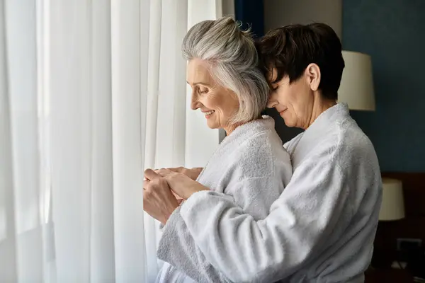 Senior lesbian couple share a quiet moment by the window. — Stock Photo