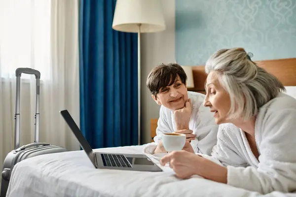 Senior lesbisch pärchen verlobt mit laptop auf bett. — Stockfoto