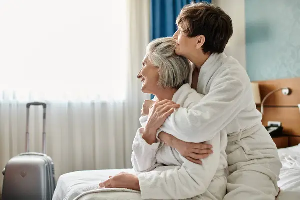 Elderly lesbian couple share a tender hug in a hotel room. — Stock Photo