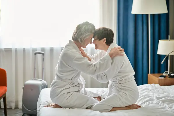 Un momento tenero tra una coppia lesbica anziana seduta su un letto. — Foto stock