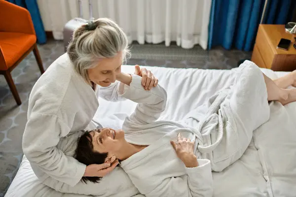 Senior lesbianas pareja tiernamente acostado juntos en un cama. - foto de stock