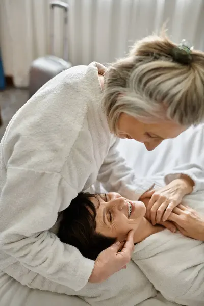 Tender senior lesbian couple in bed, one woman touches the others face lovingly. — Stock Photo