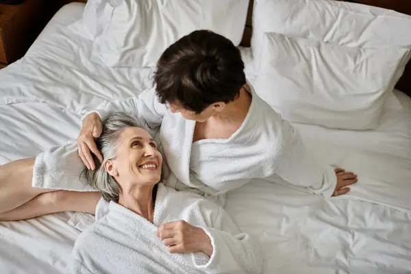 Senior lesbian couple share tender moment on bed. - foto de stock