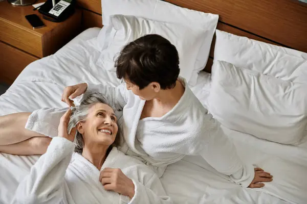 Une scène paisible de couple lesbien sénior couché ensemble au lit, partageant un moment tendre de chaleur et d'affection. — Photo de stock