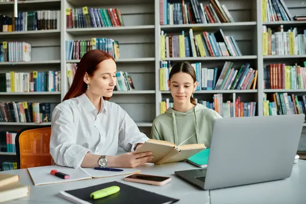 Un tutor e uno studente adolescente, assorti in lezioni post-scolastiche a un tavolo della biblioteca con un computer portatile. — Foto stock
