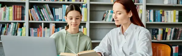 Рудий репетитор вчить дівчину-підлітка в бібліотеці, обидва вкладені в ноутбук — стокове фото