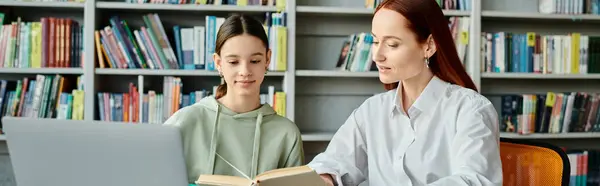 Redhead tutor teaches teenage girl in a library, both engrossed in laptop — Stock Photo