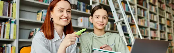 Un tutor y un estudiante que participan en una sesión de aprendizaje digital en una biblioteca. - foto de stock