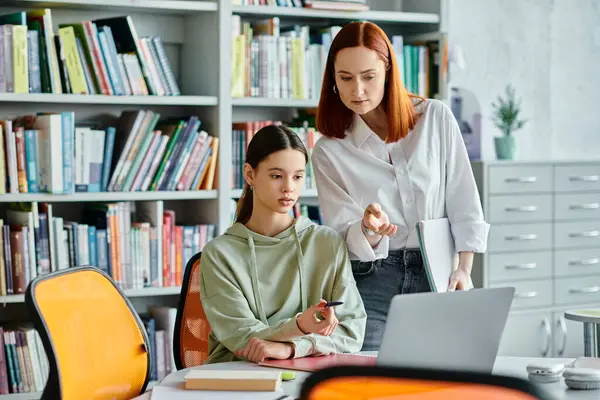 Duas mulheres, um tutor e um estudante, envolvidas em aulas pós-escolares em uma biblioteca, utilizando um laptop para a educação moderna. — Fotografia de Stock