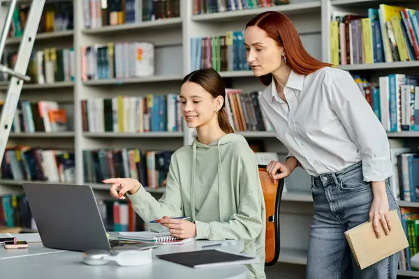 A tutor and a teenage student, engage in after-school lessons at a library using a laptop for modern education. — Stock Photo