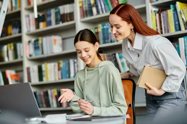 Un tutor e uno studente, impegnarsi in lezioni doposcuola in biblioteca, concentrandosi su un computer portatile per l'apprendimento digitale. — Foto stock