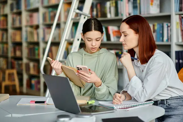 Tutor teaches teenager in a library using a laptop for modern education, engaging in interactive lessons and discussions. — Stock Photo