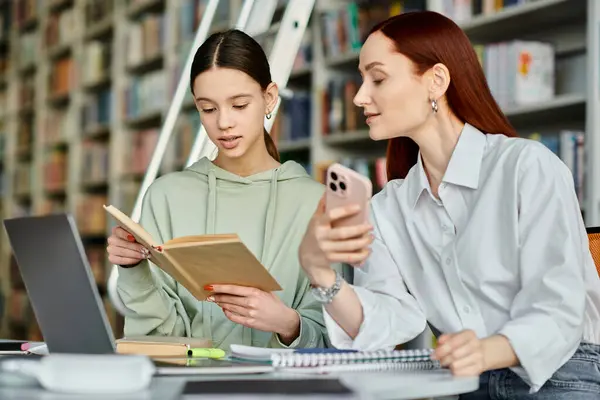 One redheaded tutor and a teenage girl, engrossed in a book at a library table, learning together. — Stock Photo