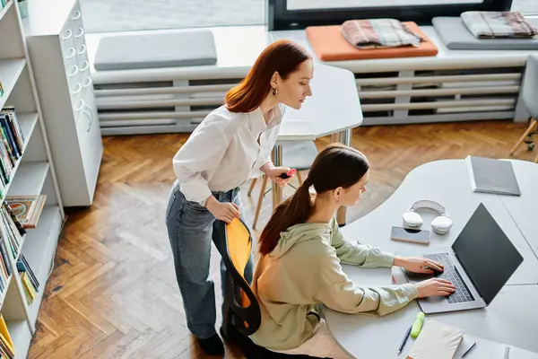 Uno tutoraggio di una ragazza adolescente, assorto in lezioni doposcuola presso una scrivania della biblioteca, utilizzando un computer portatile per l'istruzione moderna. — Foto stock
