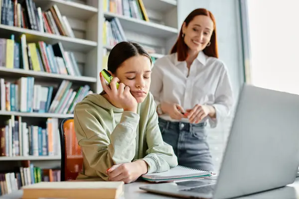 Eine fokussierte Rotschopf-Tutorin, die einem Mädchen im Teenageralter beim Telefonieren beibringt und einen Laptop für den After-School-Unterricht benutzt. — Stockfoto