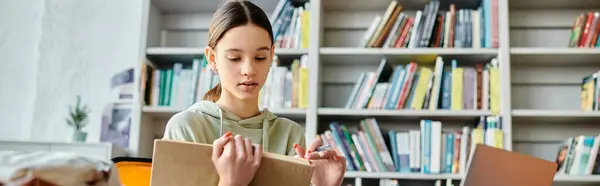Дівчина-підліток сидить за столом з книгою перед нею, занурюючись у навчання після школи. — стокове фото