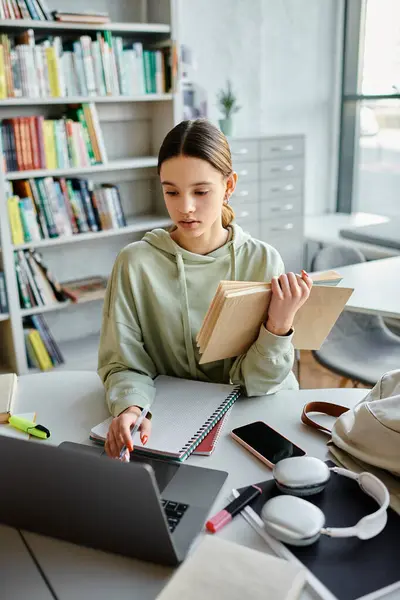 A teenage girl sits at a desk with a laptop and books, focused on her homework after school. — Stock Photo