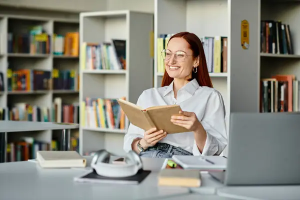 A redheaded woman engrossed in a book, surrounded by shelves of books in a library, absorbing knowledge. — Stock Photo