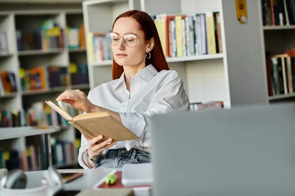 A redheaded woman engrossed in a book at a library, finding solace and knowledge amidst stacks of books. — Stock Photo